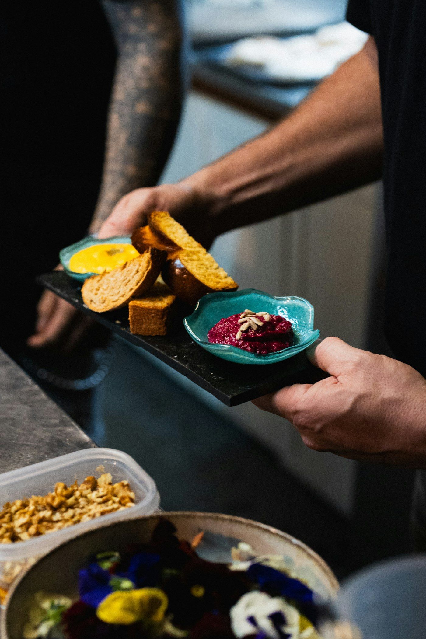 Mãos servem uma tábua com pães e pastas coloridas